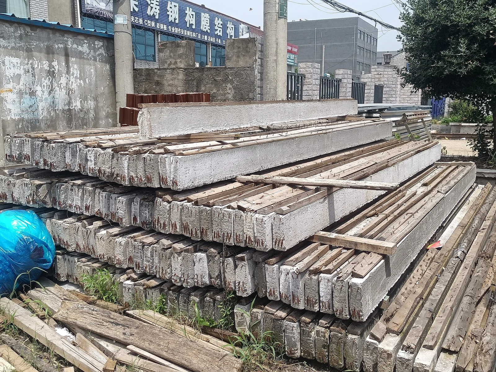 Cọc bê tông cốt thép tiết diện vuông xếp chồng thành nhiều lớp trên các thanh gỗ kê tại bãi tập kết, đầu cọc lộ thép chờ